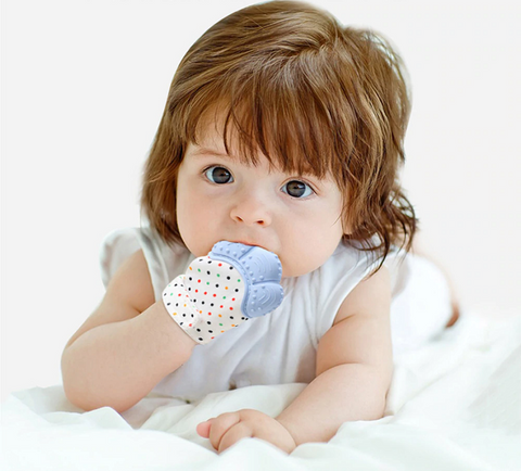 baby with teething mitten in mouth