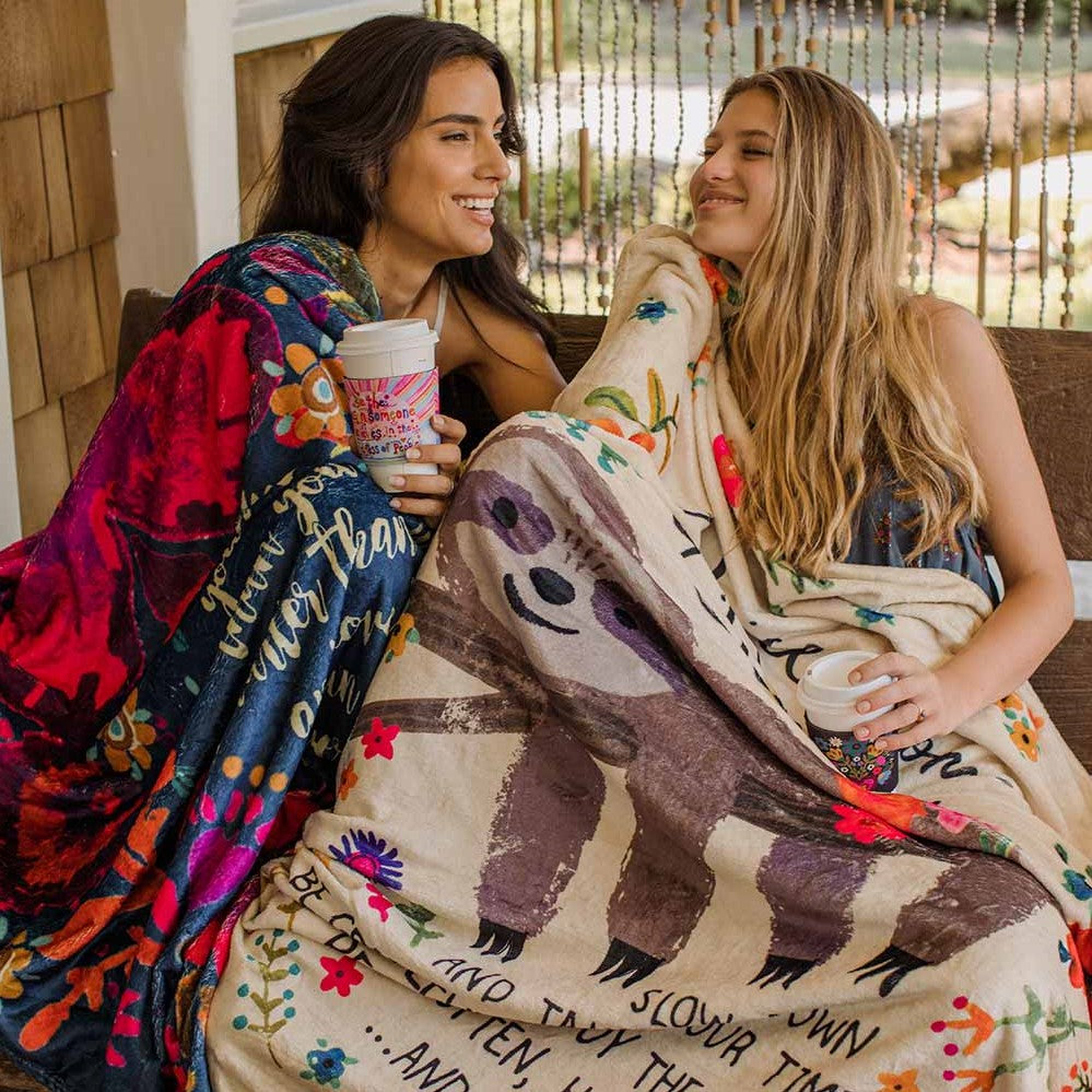 Two girls cuddling up to cozy blankets on porch