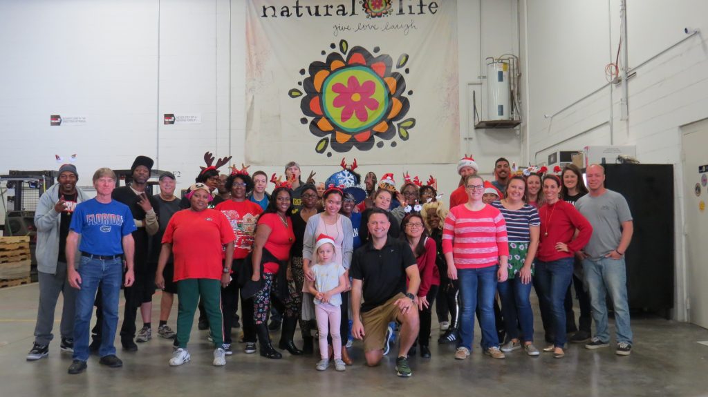 Warehouse team posing in front of Natural Life banner