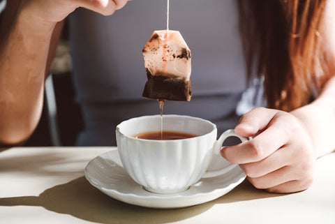 Close up of woman pulling tea bag from tea cup