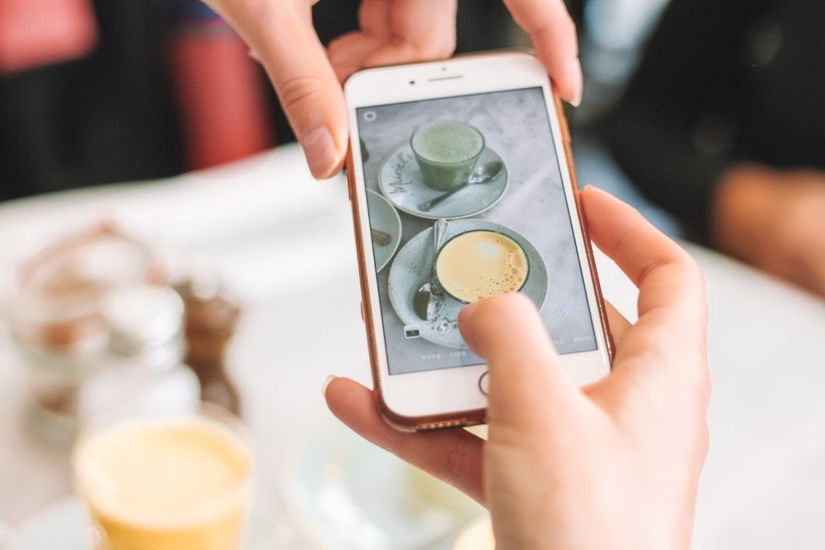 telefonla zerdeçallı latte fotoğrafını çeken kadın