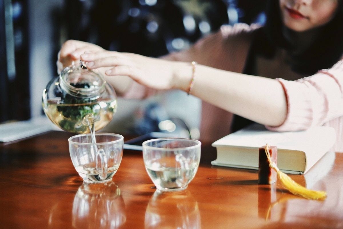 woman pouring peppermint tea into two glass cups