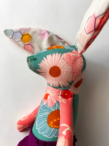 Handmade bunny rabbit stuffed animal with bright pink flowers on an aqua blue background