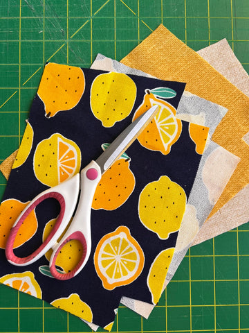 Fabric scissors laying on fabric cut to pattern for zipper pouch