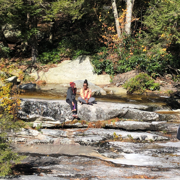 two women sitting on a ledge of cascasing water in minnewaska state park