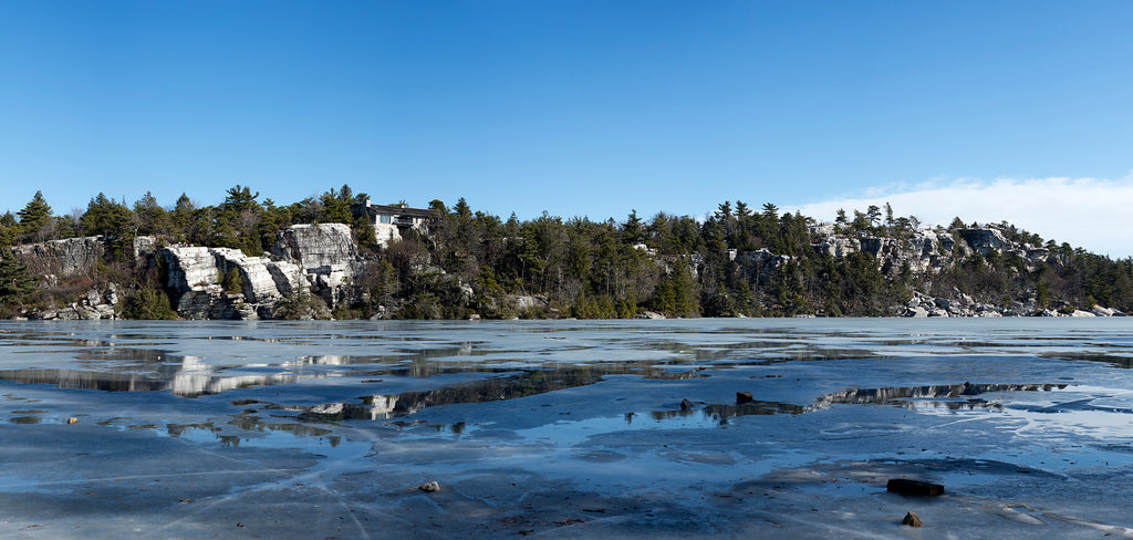 a landscape photo of a frozen lake with cliffs in the background