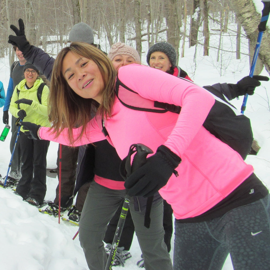 a group of hikers on snowshoes pose in a line on a snowy trail