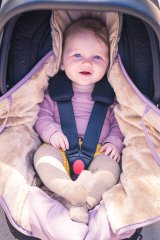 Baby der sidder i autostol med lilla autostolspose fra Sleepbag