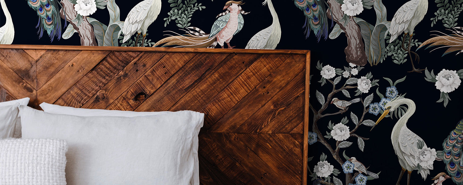 Bed next to a wallpaper with a bird pattern