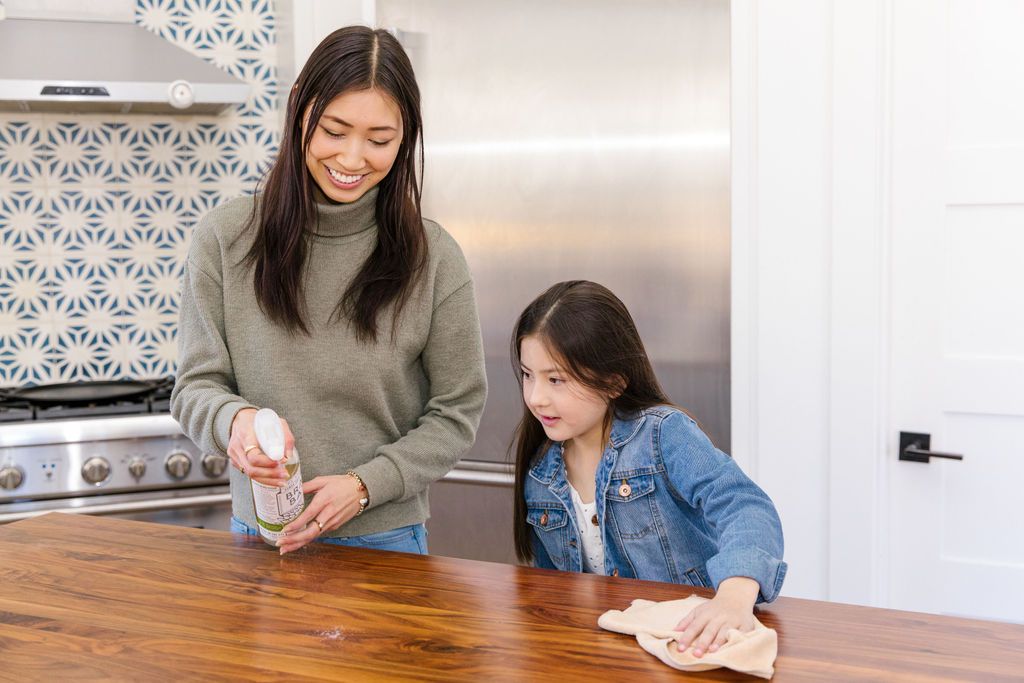 Mother and daughter wiping counter with branch basics