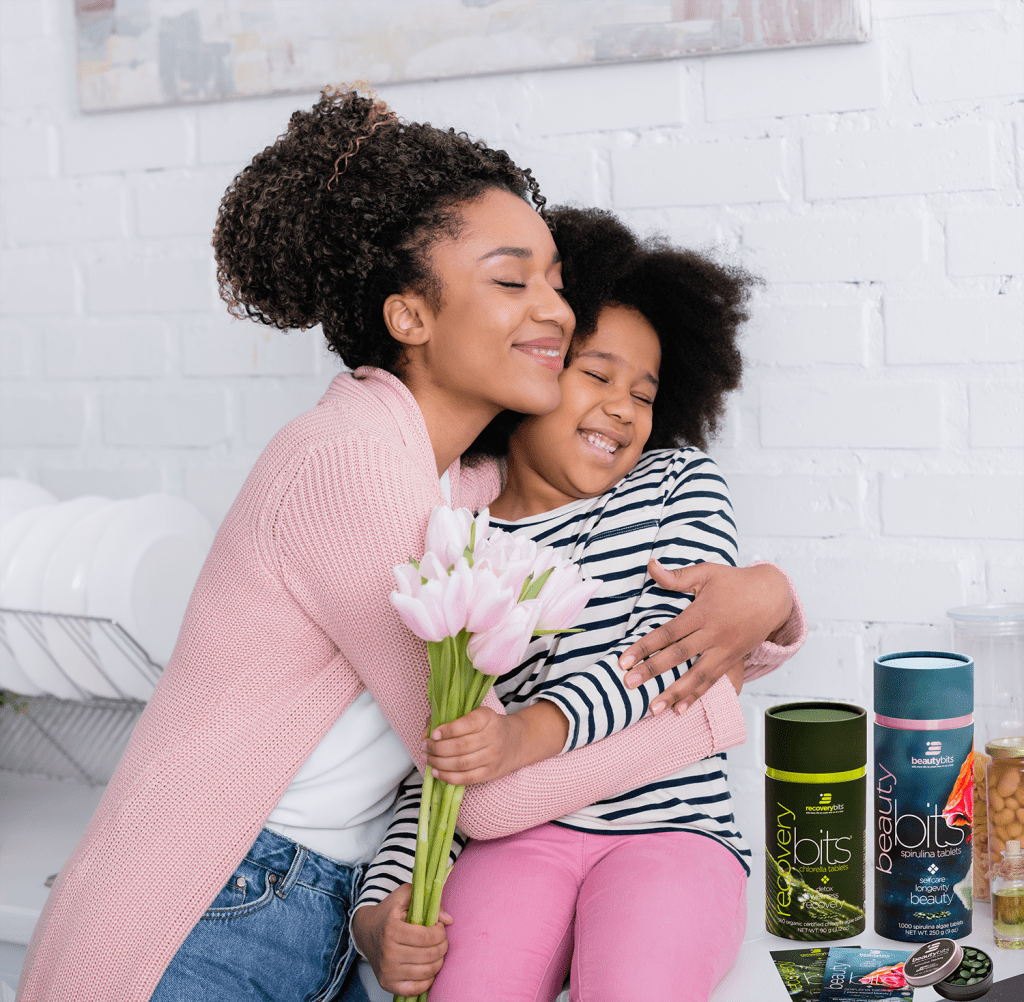 Mother and daughter hugging with tulips and ENERGYbits products. 