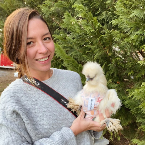 studio cluck founder & owner Leanne Luce, holding her favorite chicken Blanche wearing a chicken harness