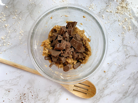 bowl of cookie dough and big chocolate chunks and wooden spoon