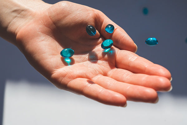 a person holding blue liquid pills 