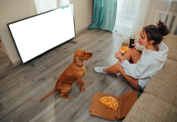 young female watching a television show with her dog 