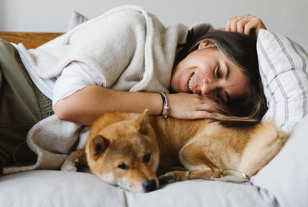 A happy woman lying on the sofa with a cute purebred dog