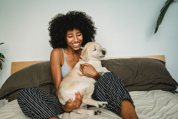 a woman keeping her puppy warm in bed