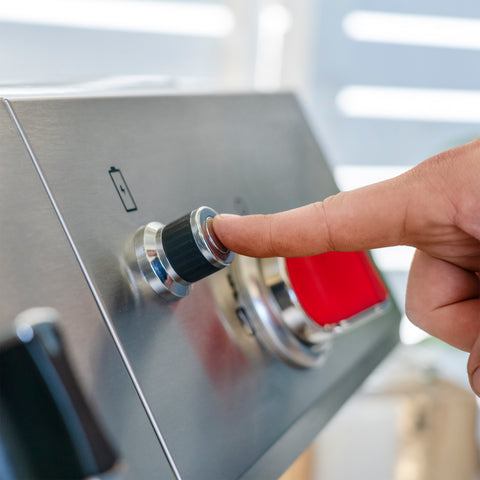 hand pressing ignition started button on a gas grill