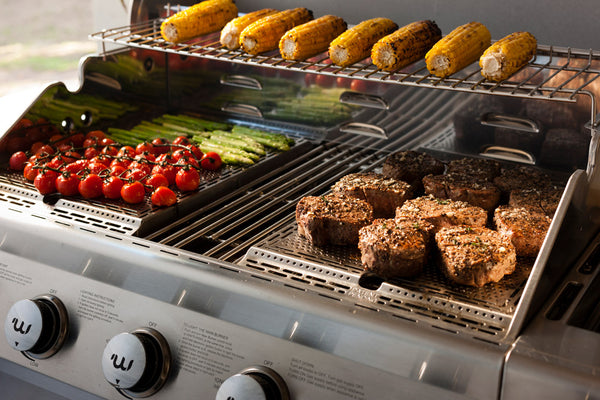 Variety of foods grilling on a gas grill surface