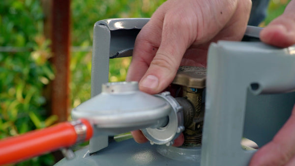 close up of a gas grill regulator connected to a propane tank