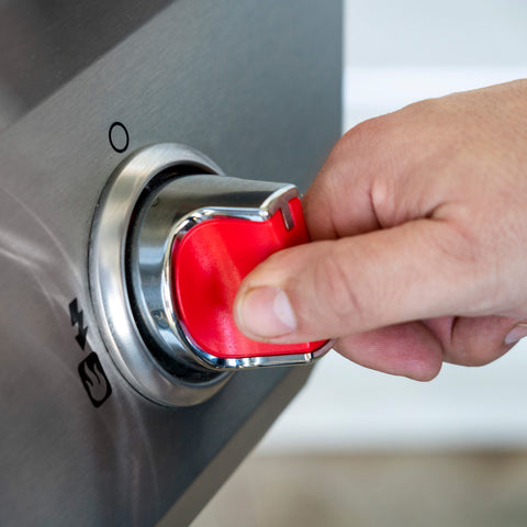 hand pressing the ignition starter button on a gas grill