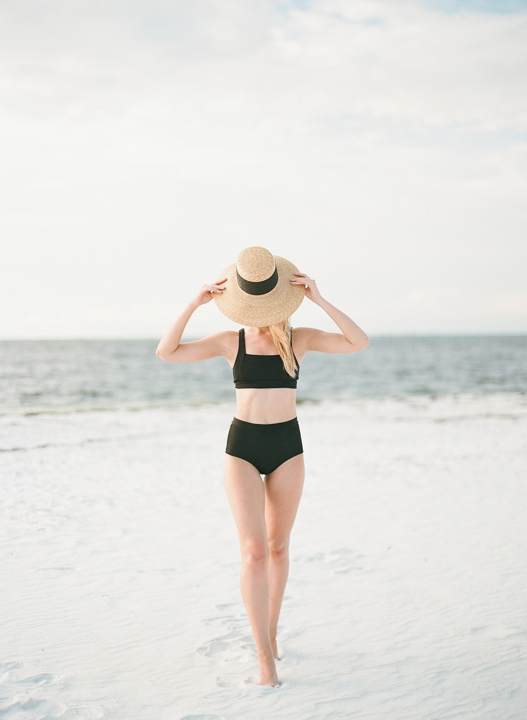 woman wearing black bathing suit with hat at the beach