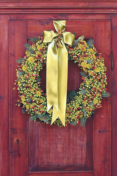 Idée décoration noël porte d’entrée avec couronne verte et baies rouges