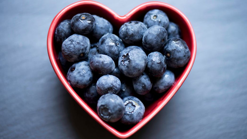 A heart shaped bowl full of blueberries. 