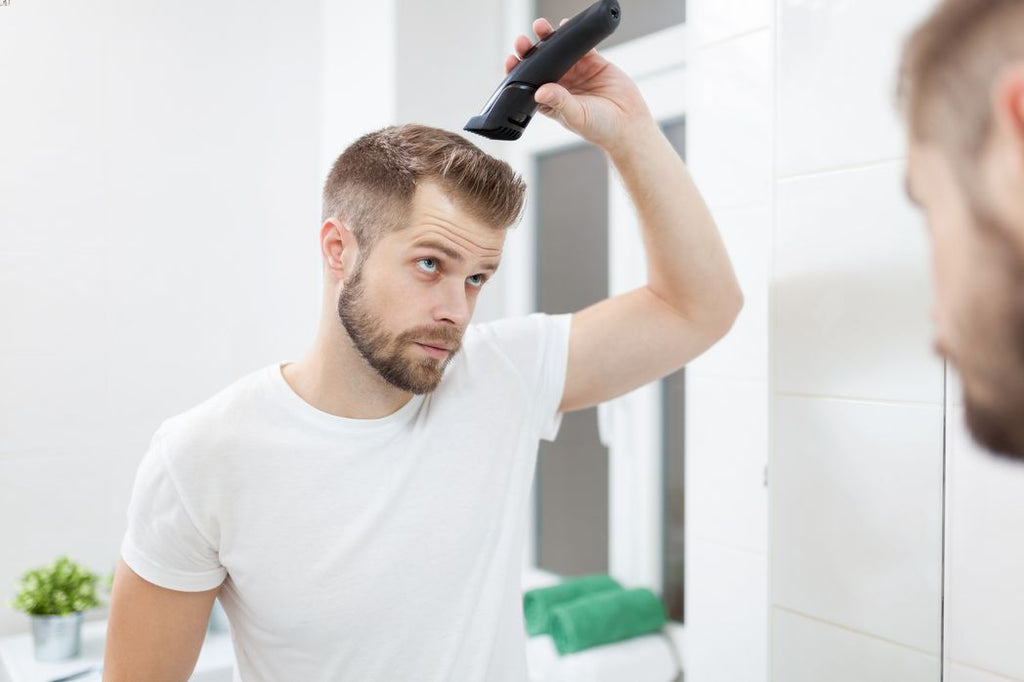 Man using clipper to cut and trim his hair.