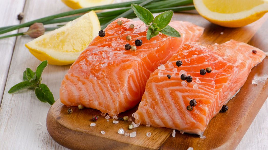 A plate of salmon with lemon slices.