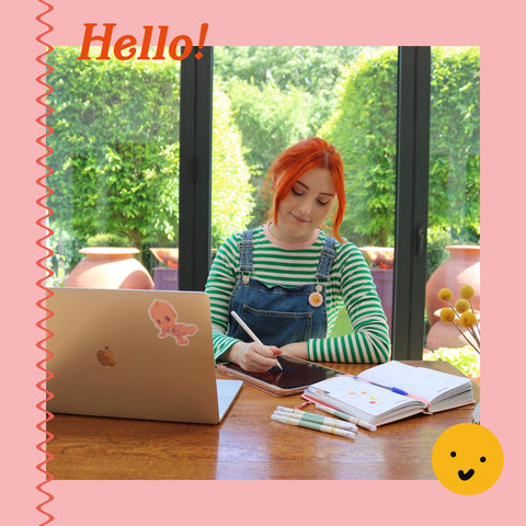 image of a young woman drawing at a desk sat in front of a lush garden.