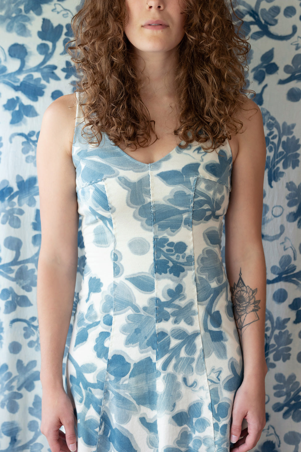 Alabama Chanin Niko Dress featuring hand-sewn seams and painted floral motif. Shown on model in Natural color with indigo flowers.