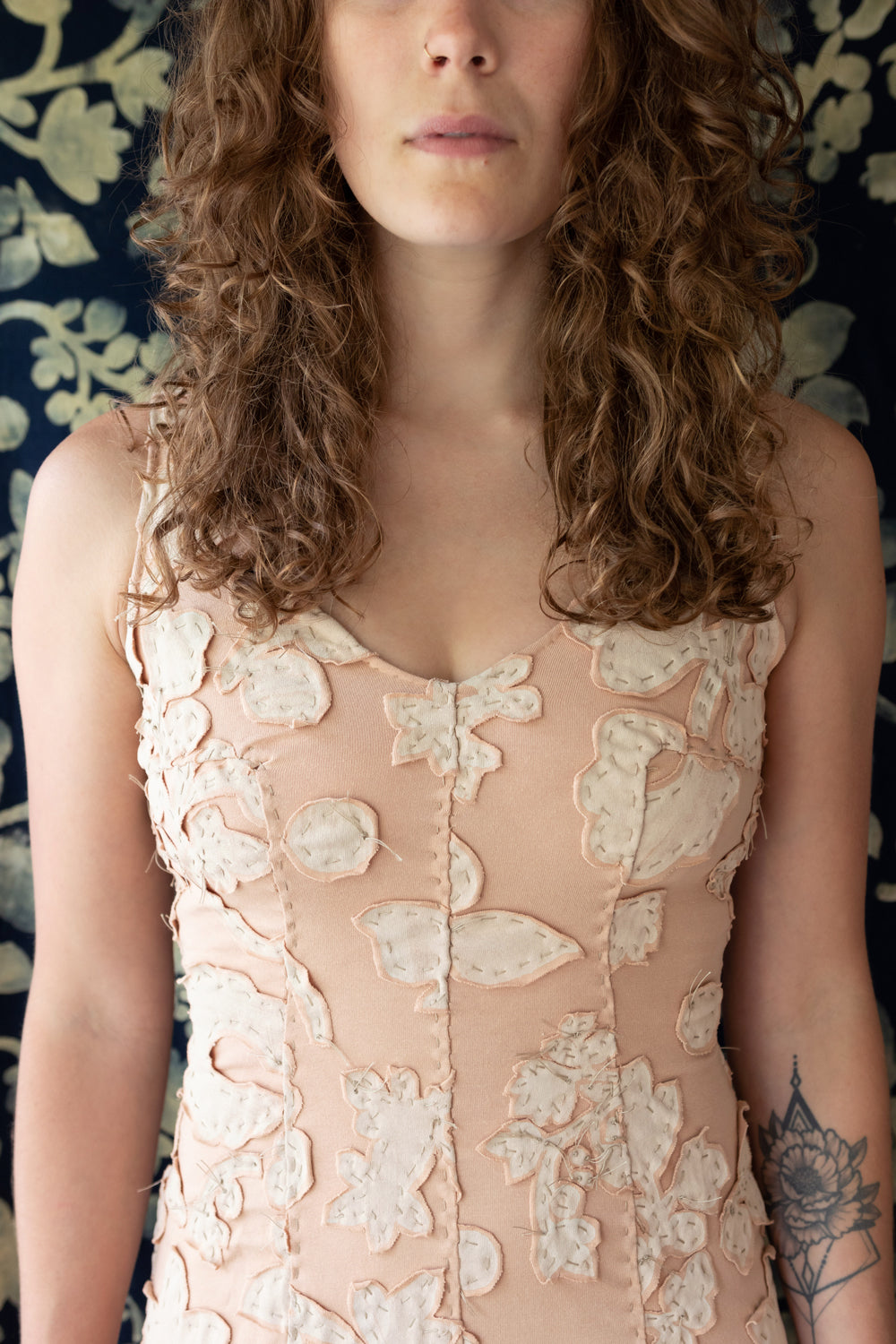 Model wearing the Carrington Dress with hand-sewn seams and floral appliqué. Shown in vetiver pink color.