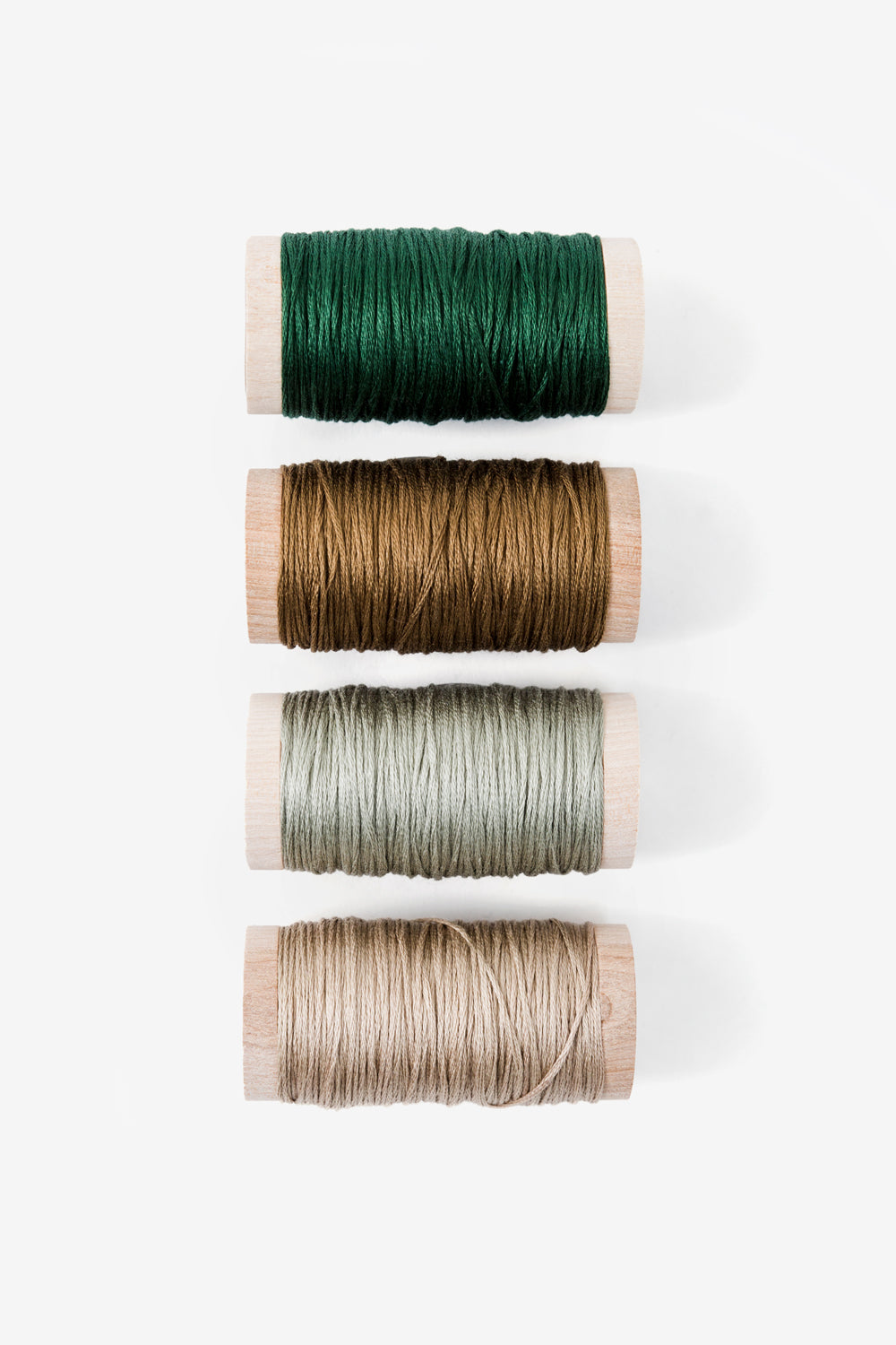Spools of embroidery floss in forest, ochre, sage, and dogwood.