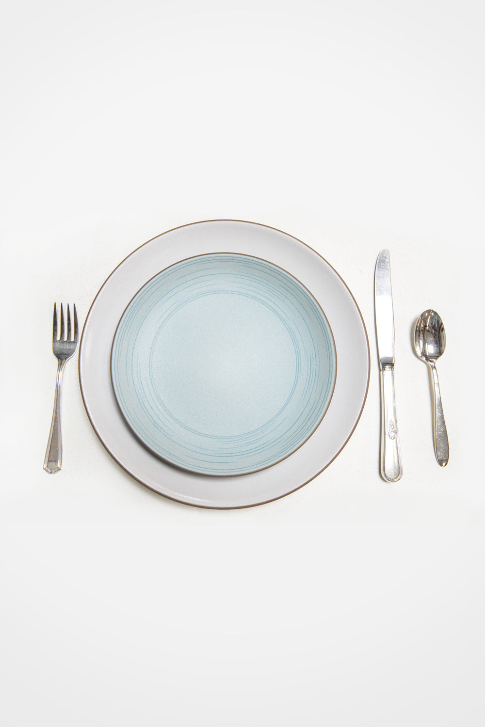 Heath Ceramics Etched Salad Place in Limited Edition Wave Blue Color. Shown on top of Opaque White Dinner Plate.