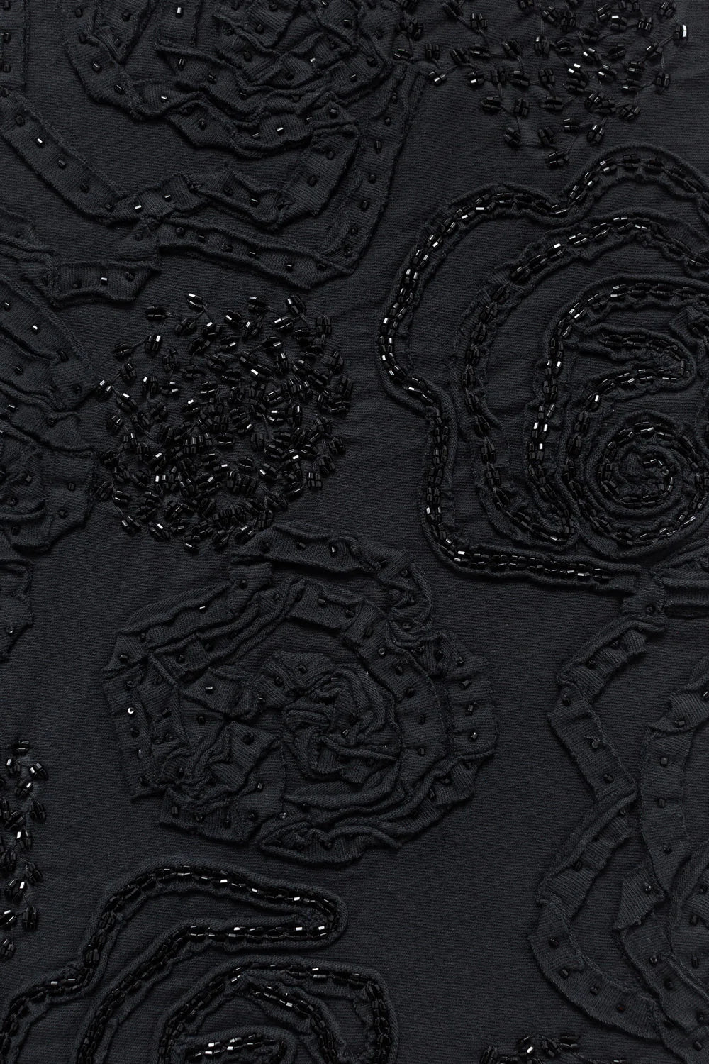 Detail of a swatch featuring black rose appliqué on black fabric.