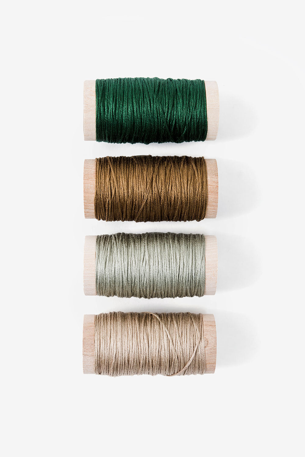 Four spools of embroidery floss in green and tan colors.