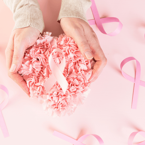 female hands holding flowers and a breast cancer symbol