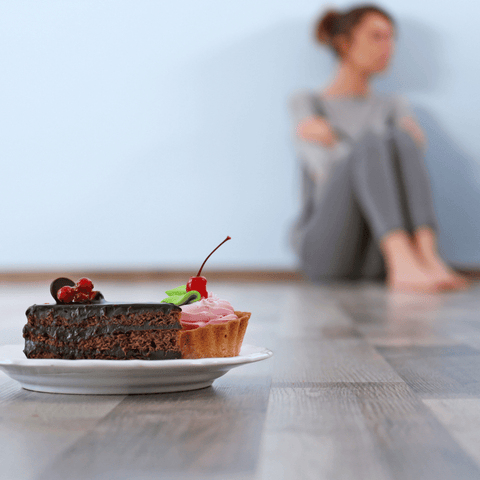 girl sitting far away from two slices of cakes