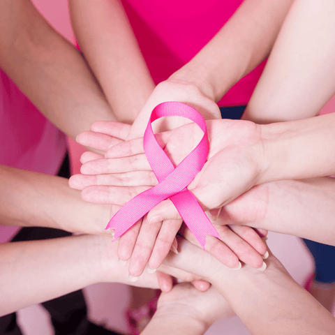 many female hands holding a breast cancer symbol