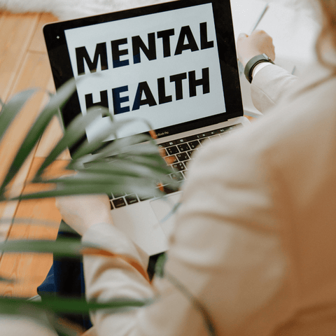 a woman looking at computer screen that says mental health