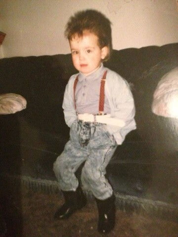 Founder Kaye as a child in the 1980s wearing stonewash jeans, braces, black boots and a mullet.