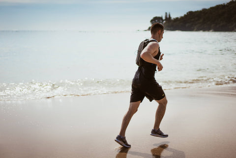 Man running in beach with earphones on 