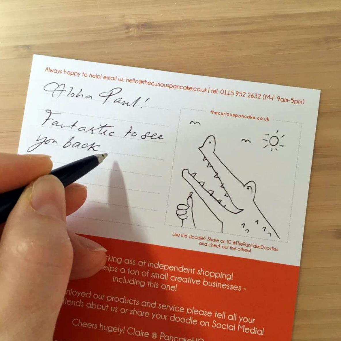 Handwriting a thank you note for a customer with a doodle of a crocodile.