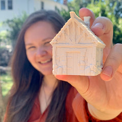 A woman holding a 3D printed house smiling at the camera