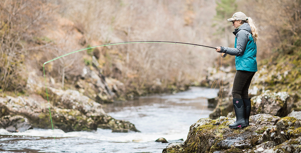 Woman fishing by the river bank