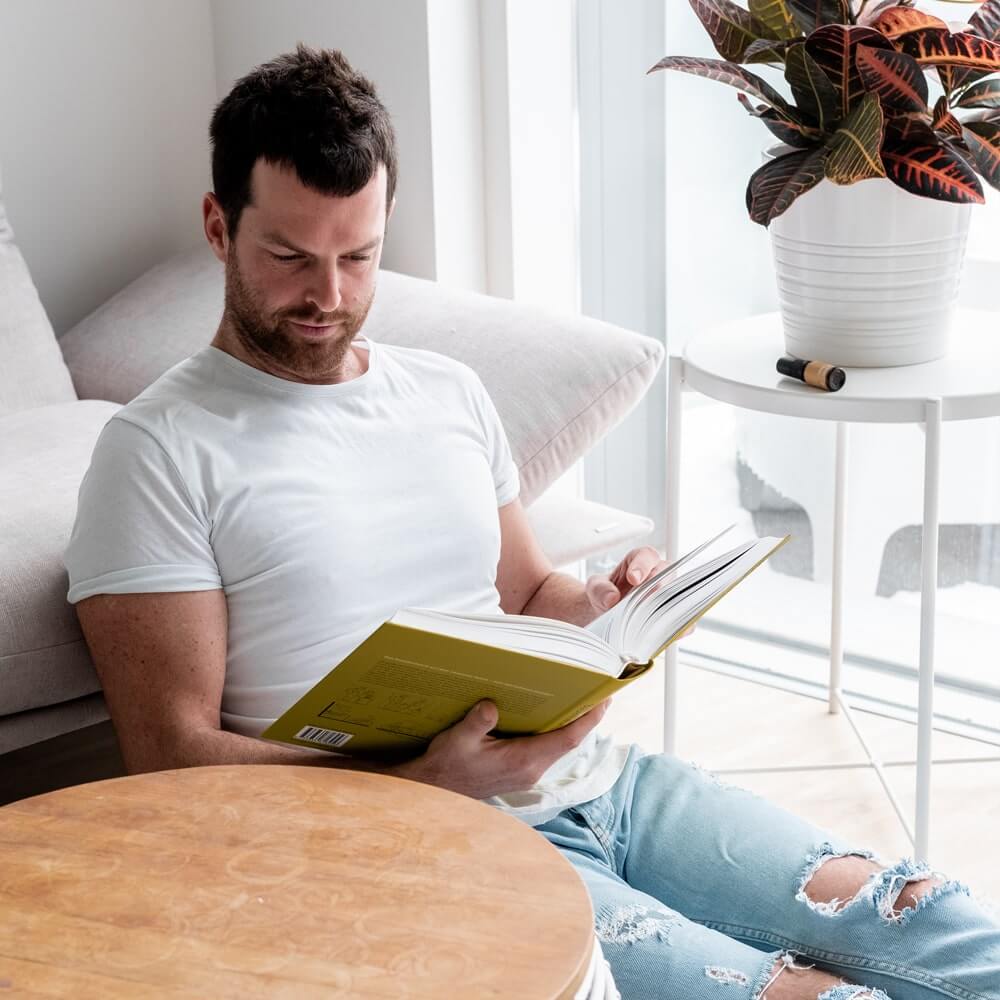Junger attraktiver Mann liest entspannt ein Buch