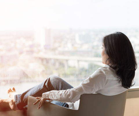 woman sitting down relaxing in front of a window with her feet up looking at the view