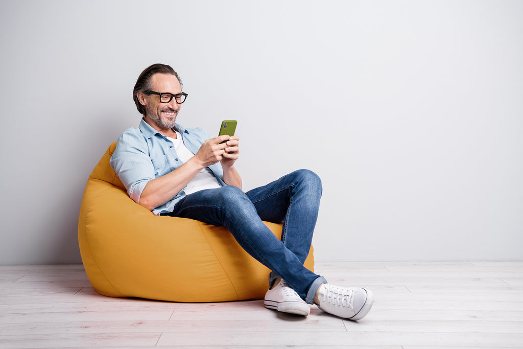 middle age man on iPhone in an orange bean bag chair