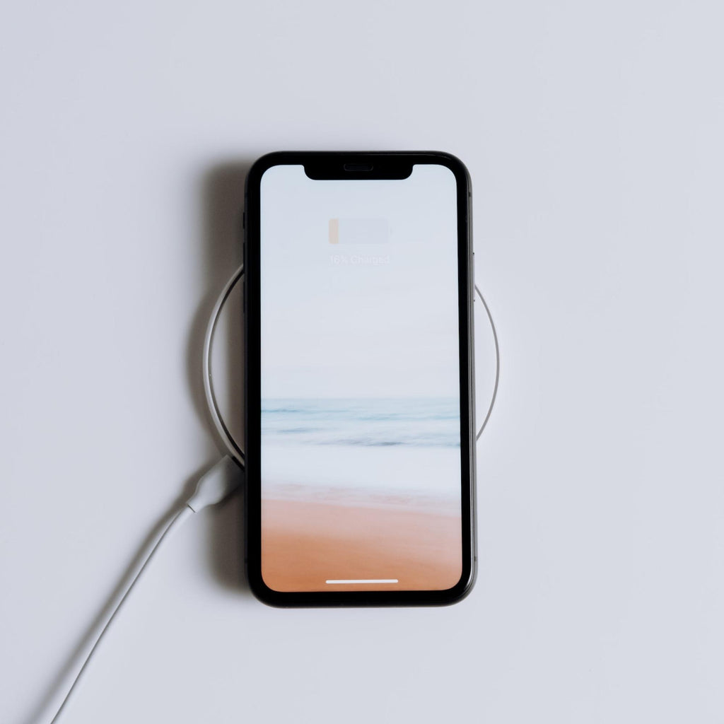 image of an iPhone on a MagSafe charger. Beach image on lockscreen